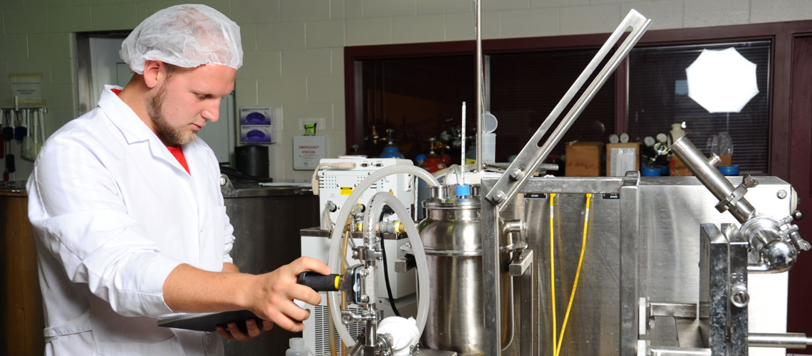 A male student in a lab coat is conducting research.