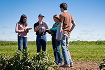 Four students holding notebooks stand in a field.