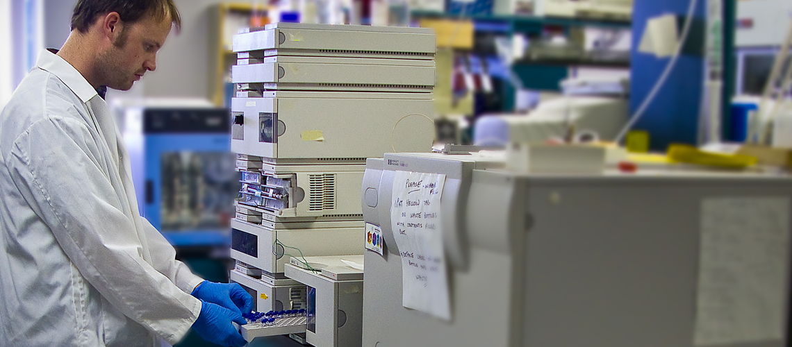 Male student in lab coat working with large sampling equipment