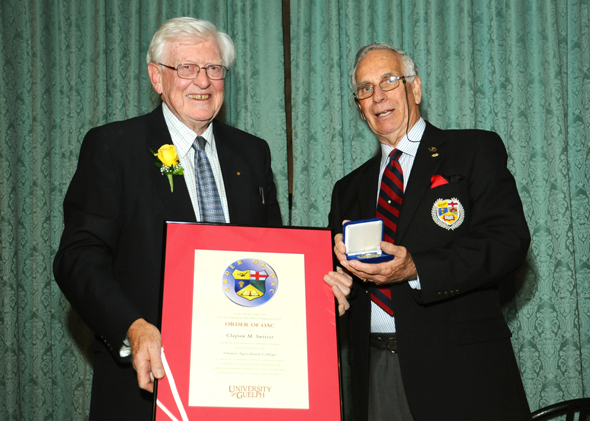Clay Switzer at his Order of OAC induction ceremony, holding certificate, with Bruce Christie