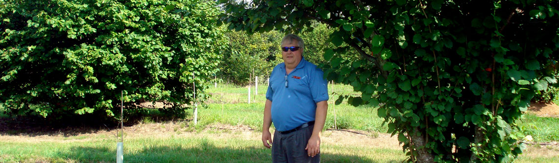 Martin Hodgson stands under hazelnut tree.