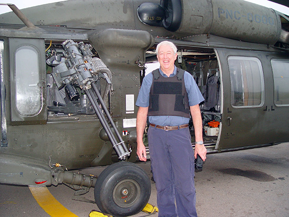 Keith Solomon stands in front of armoured helicopter with bullet proof vest on