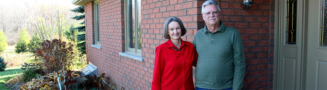 Doreen and Ron McCracken standing outside of their red brick home
