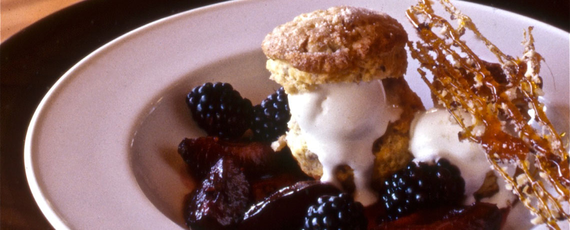 Picture of poached plums and hazelnut shortcake served in a white bowl.