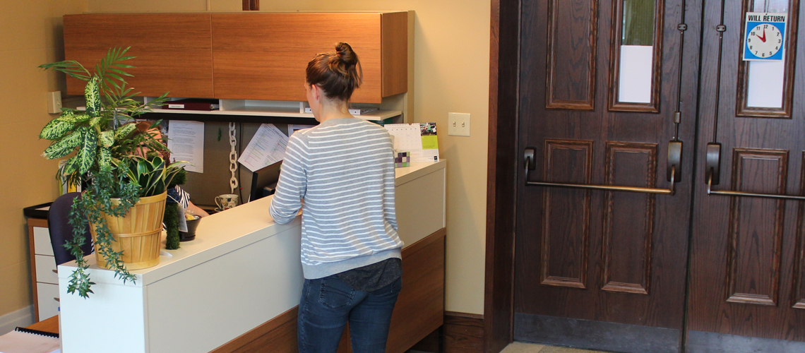 Student stands at desk speaking to staff behind it