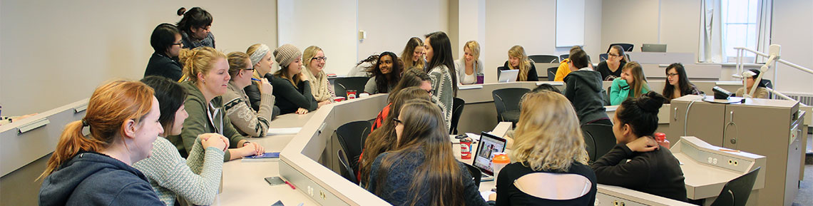 Students sit in lecture room facing each other and working together