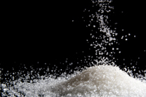 White salt is sprinkled into a pile on a black background.