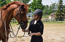 Julia stands next to brown horse.