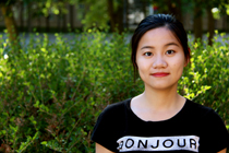 Headshot of Katherine standing in front of green shrubs.