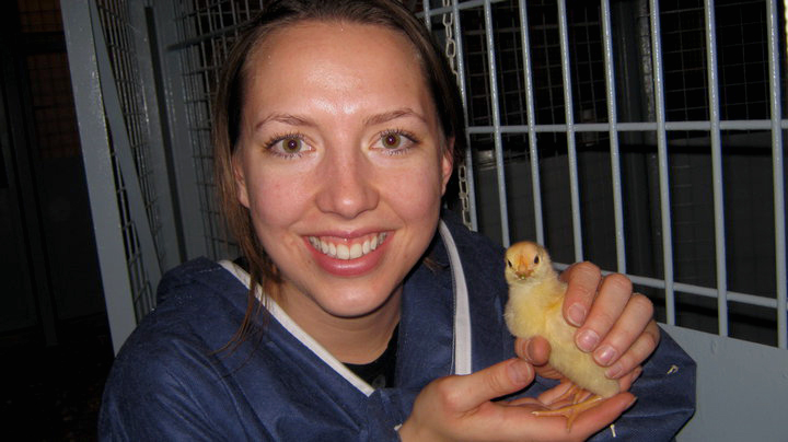 Krysta holds up a small yellow chick.