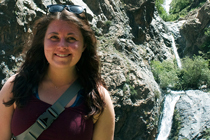 Laura Stortz stands in front of a small waterfall.