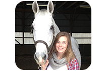 Lucy Pronk stands in barn with horse.