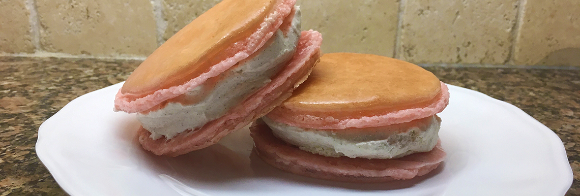 Two macaron ice cream sandwiches sit on a plate.