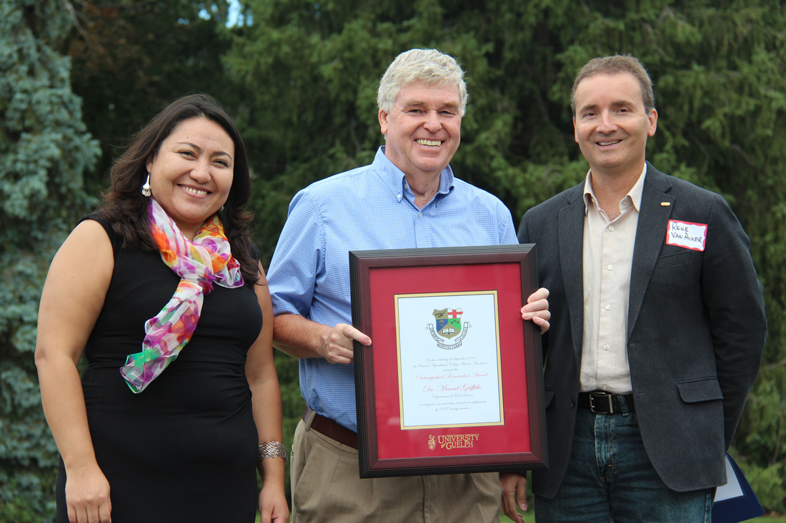 Rocio Morales Rayas, Mansel Griffiths and Rene Van Acker pose outside with framed certificate