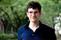 Head shot of Michal standing under trees.