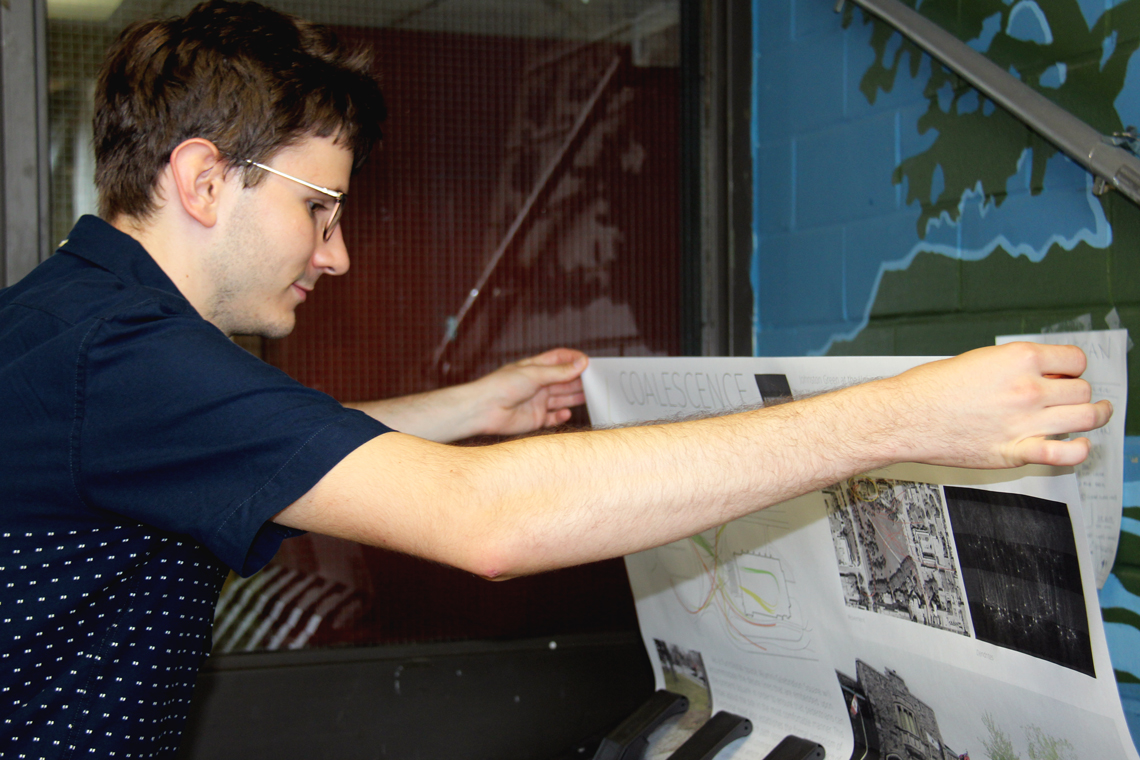 Michal guides his poster out of a large printer.