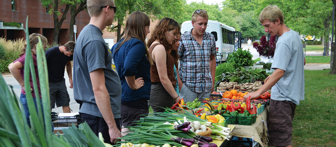 People buying vegetables at a stand. 