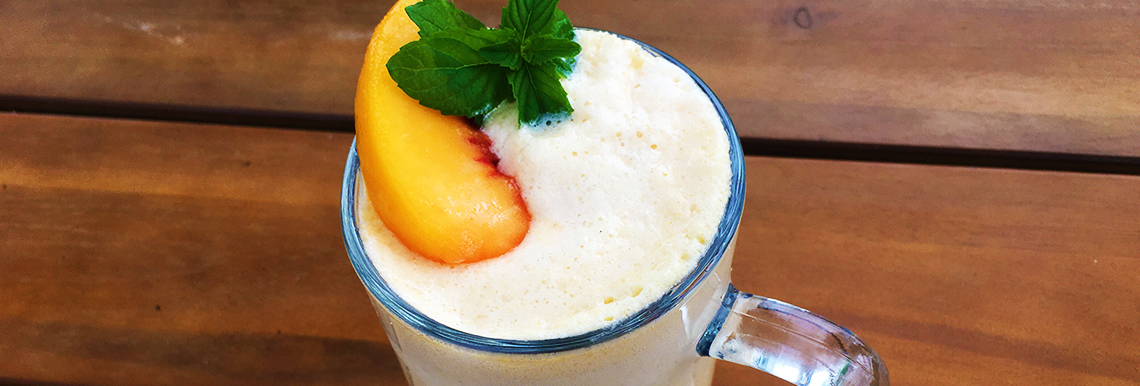 A peach smoothie sits on a table.