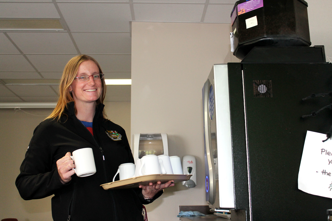 Sara holds a tray of mugs at the coffee cart.