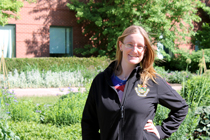 Sara poses in gardens wearing black jacket.