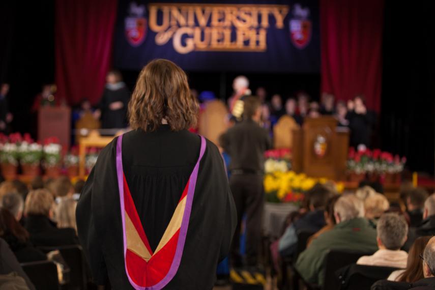A student in her graduation gown walks up to the stage to receive her degree.
