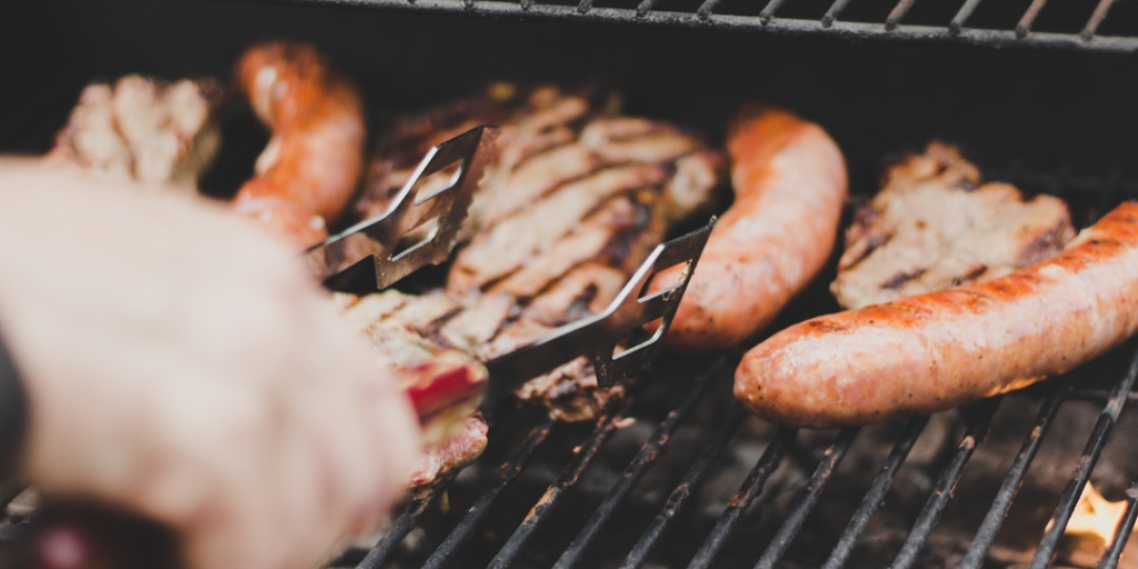 A person flipping meat on a barbecue.