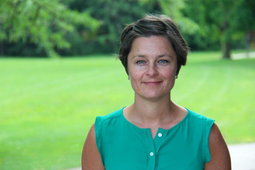 Prof. Kate Shoveller stands outside in front of a green lawn.
