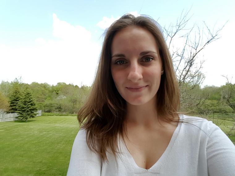 Head shot of Krista standing on a green lawn with a forest in the background.
