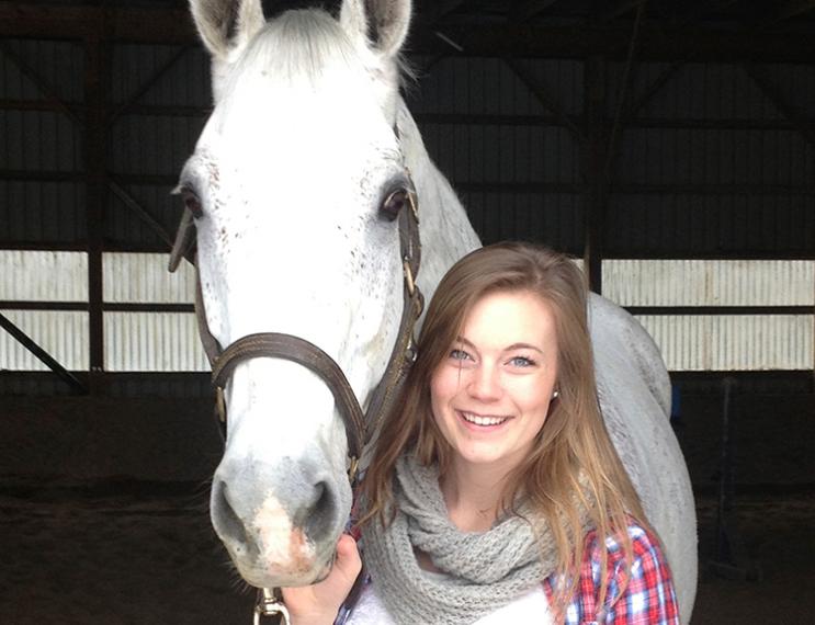 Lucy stands with her white horse