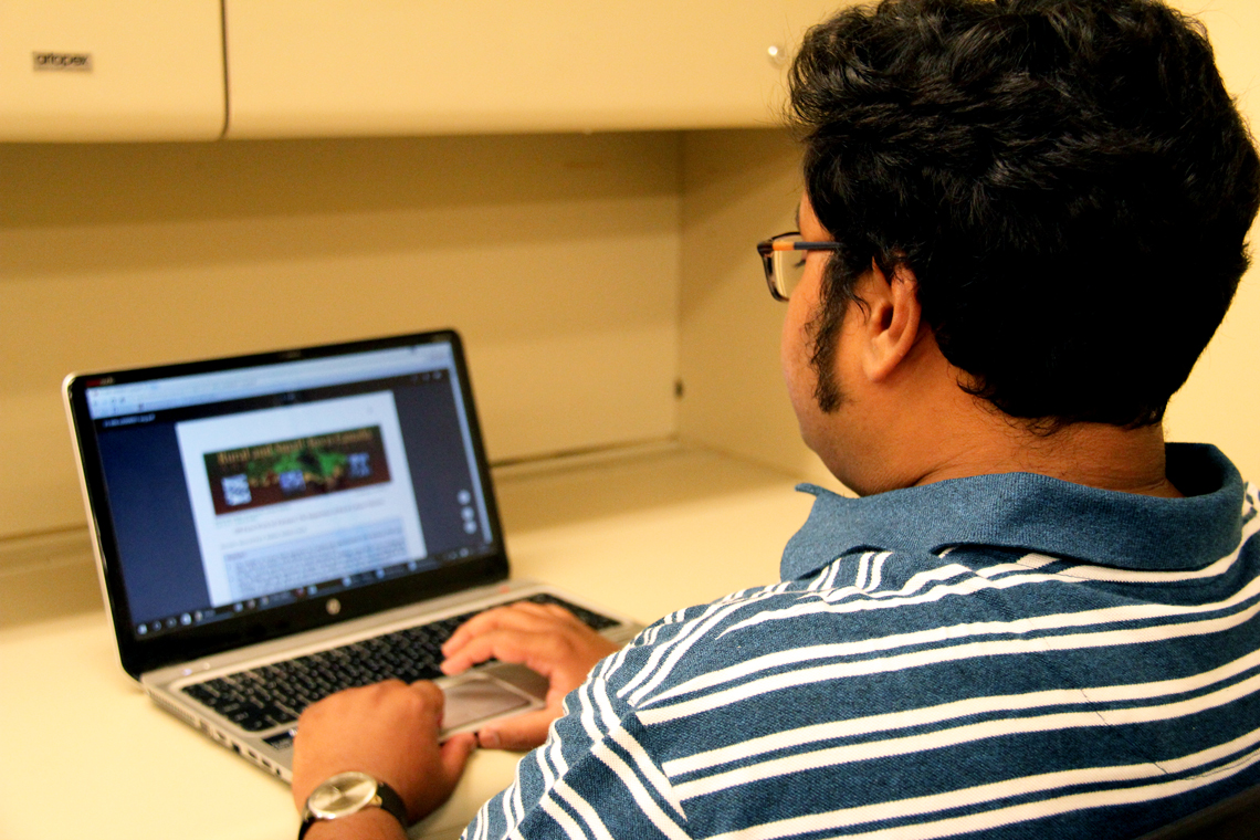 Syer works on computer at desk.