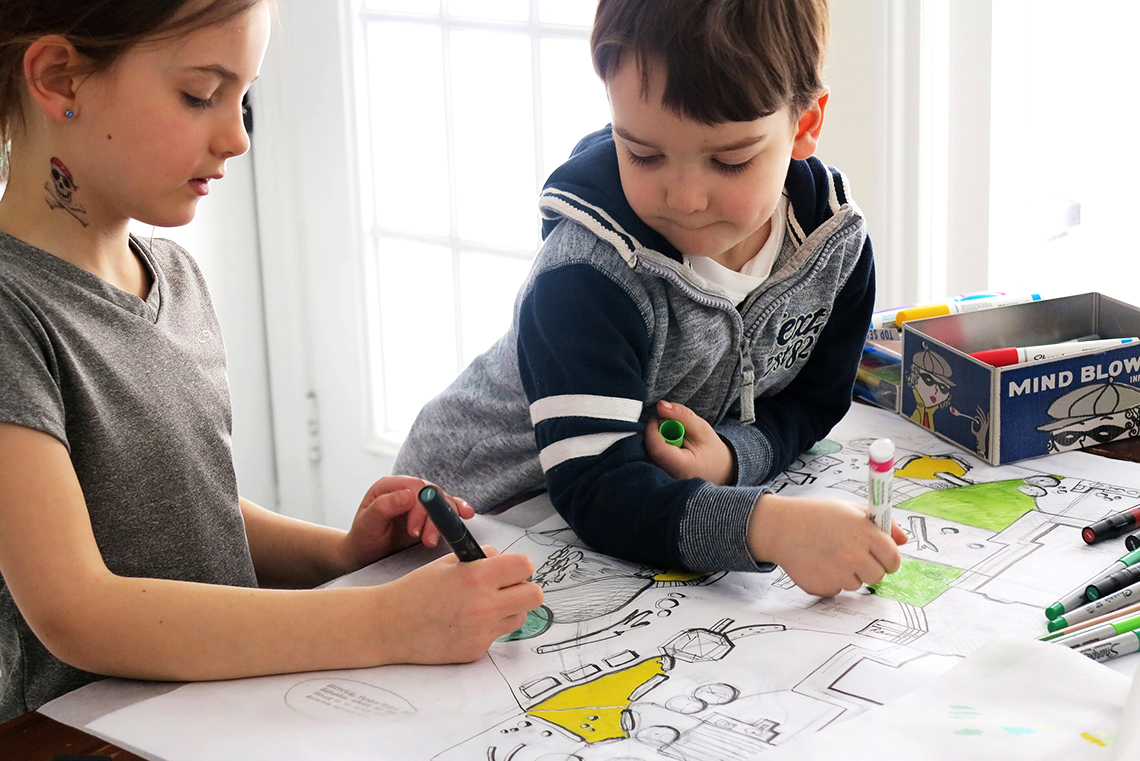 Two children help colour in a sketched design.
