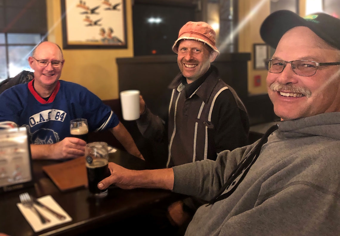 Three men smiling at a dinner table