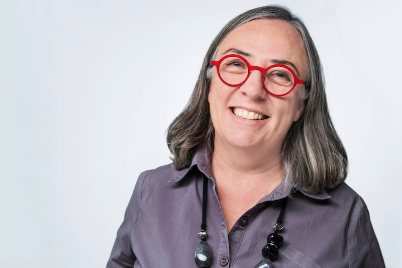 Gillian Siddall wearing bright red glasses and a big smile.