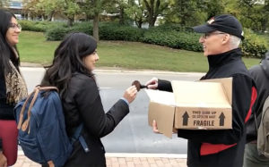 President Dr. Franco J. Vaccarino handing out cookies at the bus stop to students going home