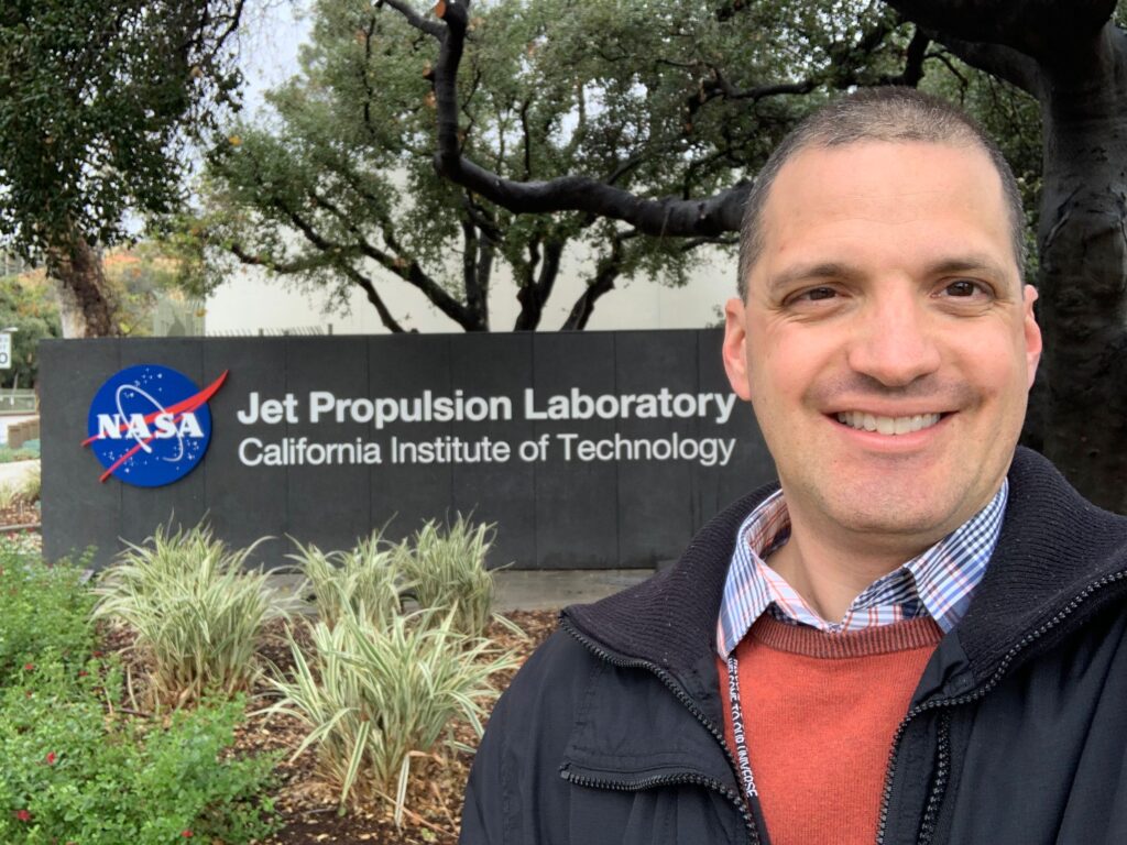 closeup smiling man before sign saying NASA Jet Propulsion Laboratory