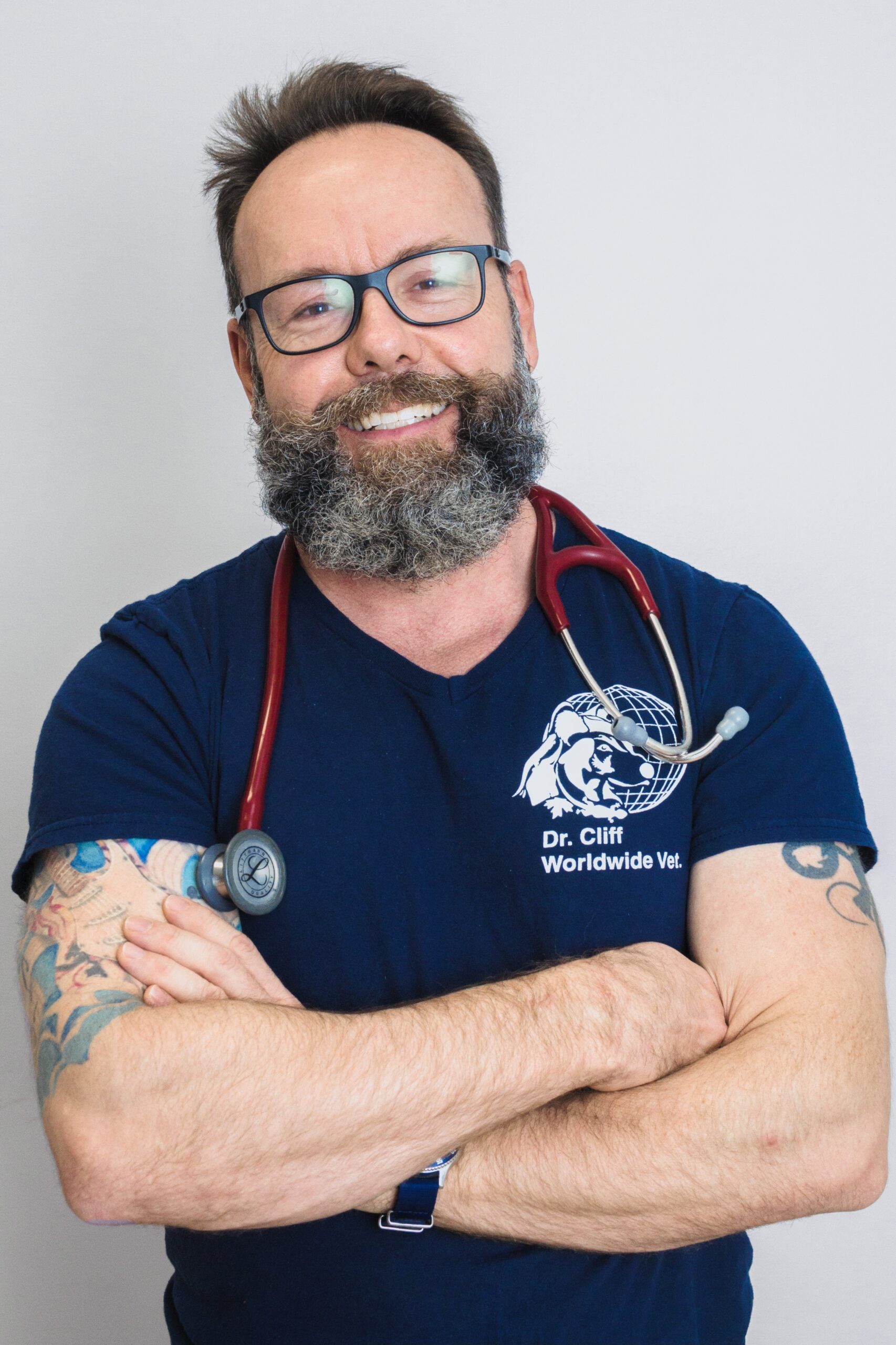 bearded man in T-shirt with stehescope smiles at camera