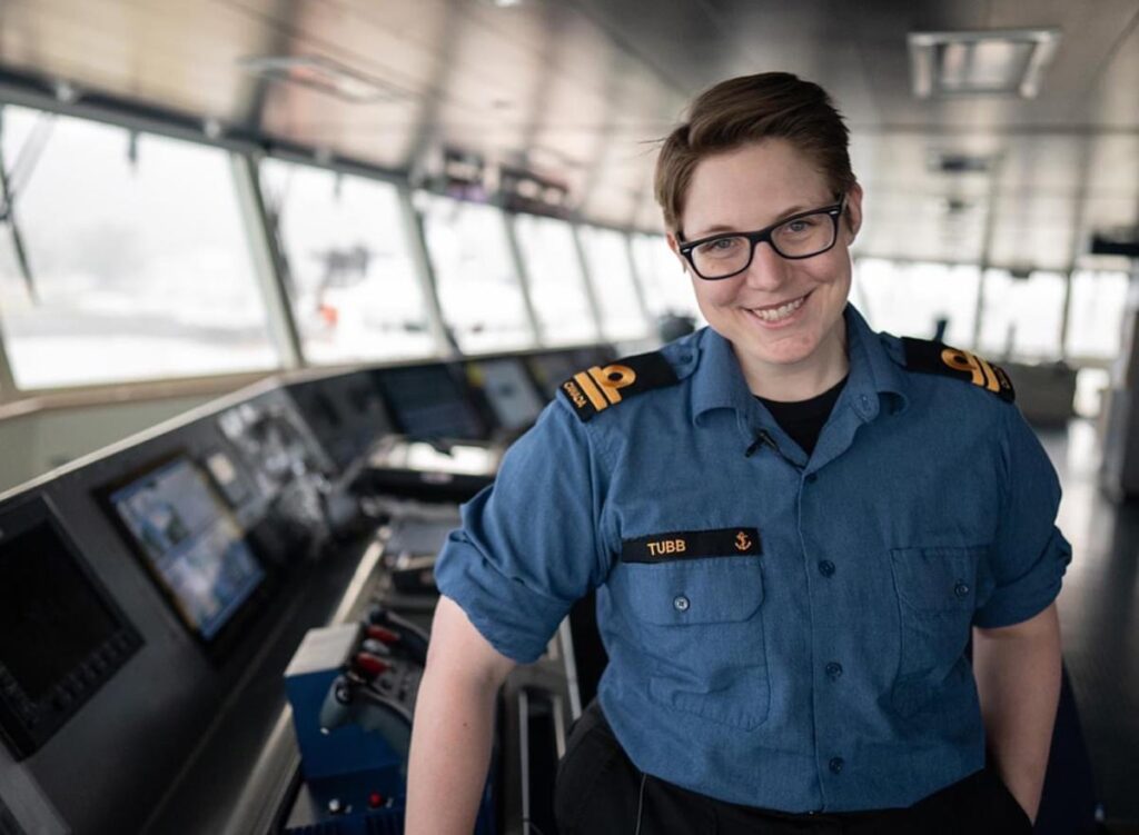uniformed woman aboard ship smiles at camera