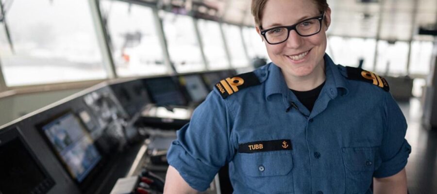 uniformed woman aboard ship smiles at camera