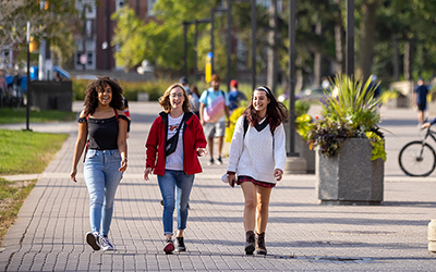 A group of three students walking on a brick path on the University of Guelph campus