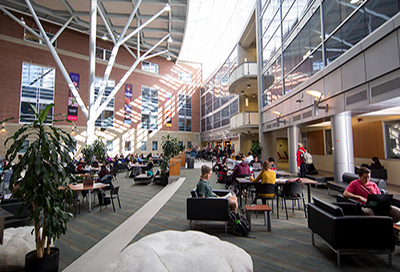 Students sitting at tables in the atrium of the Summerlee Science Complex