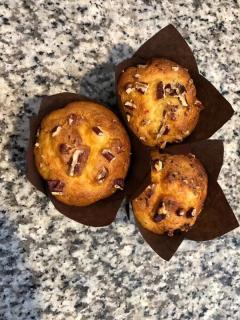 Three muffins with brown paper wrappers on a grey speckled counter. 