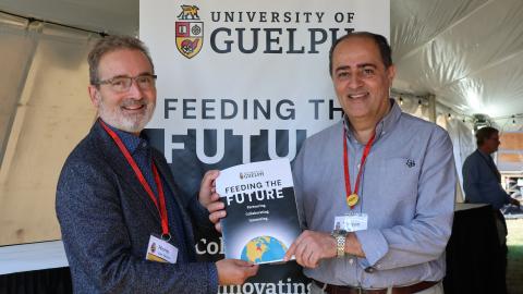 Rene Van Acker and Shayan Shariff holding a copy of the Feeding the Future report. 