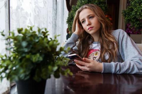 Girl sitting at a table with a cell phone in her hand