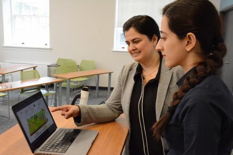Rozita Dara with a student pointing at a computer screen on a table.