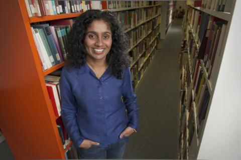 Sharada Srinivasa standing in front of a shelf of books in the library