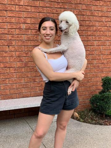 SPARK writer Sydney Pearce holds her dog Riley, a white poodle-cross, in her arms.