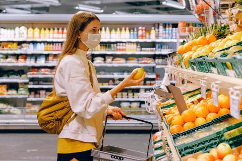 A woman in a grocery store holding a lemon