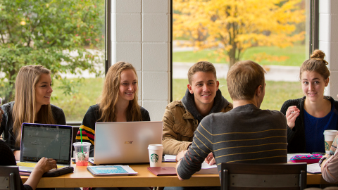 A group of U of G students sitting around a table and talking.