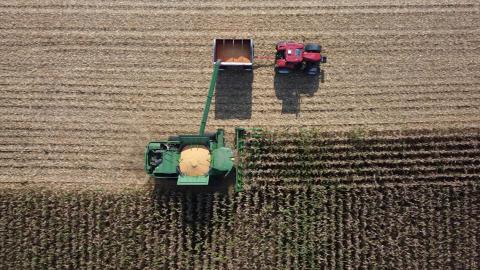 An aerial view of a field with a tractor plowing crops as part of agri-food research operations.