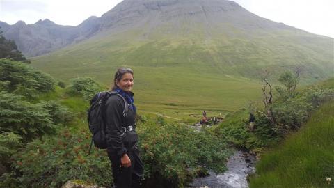 Susan Chiblow standing in a valley with a backpack on and a mountain in the distance.